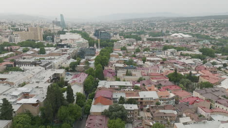 Pan-left-drone-shot-of-the-foggy-Tbilisi-panorama-and-crowded-neighborhood