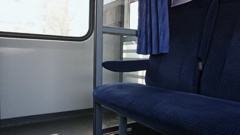 inside of moving train, empty blue passenger seat in compartment close up