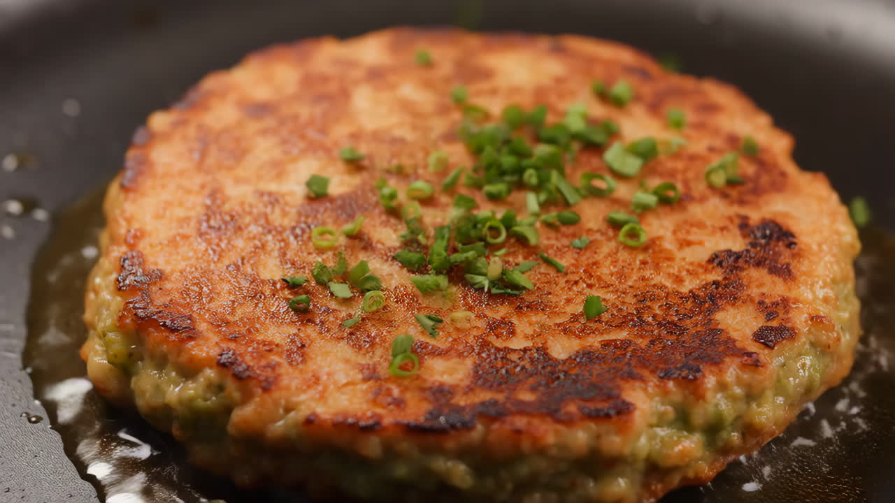 Frying a golden-brown patty with chives in a pan