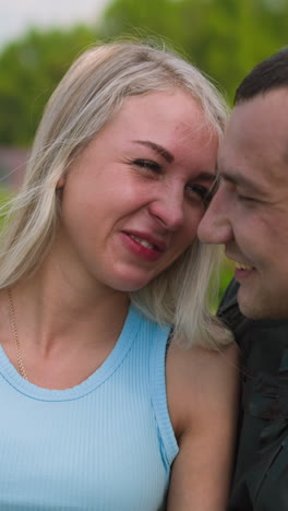 pretty joyful woman smiles sitting with beloved man in leather moto jacket at countryside on sunny spring day close view slow motion