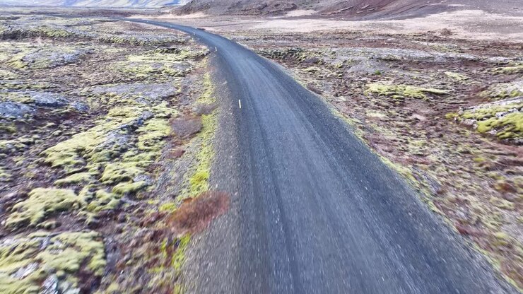 A view of a car passing from barren land on a road towards its destination in Iceland