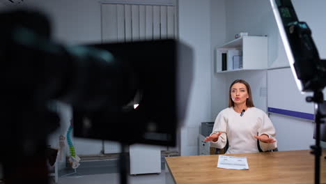 beautiful woman speaks focused on camera. female blogger records video for her blog. focus on speaker and then on camera display.