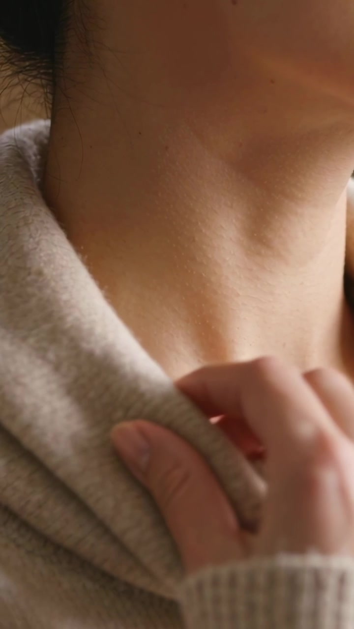 Donna che sistema un colletto a maglia in un primo piano di moda, una mano che tira il tessuto per rivelare la scollatura.