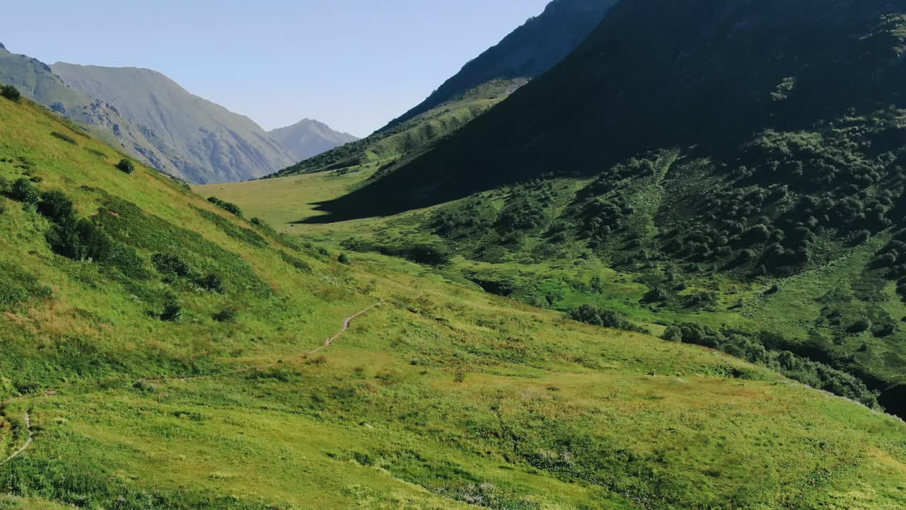 Vista dal sentiero d'alta quota nelle montagne del Caucaso con ghiacciai, erba verde e laghi selvaggi.