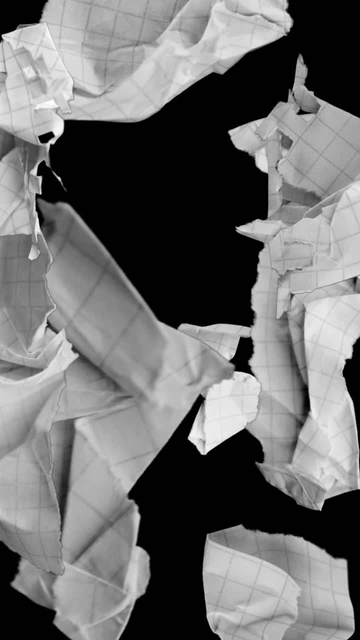 Crumpled Grid Paper Scraps Falling Against a Black Background