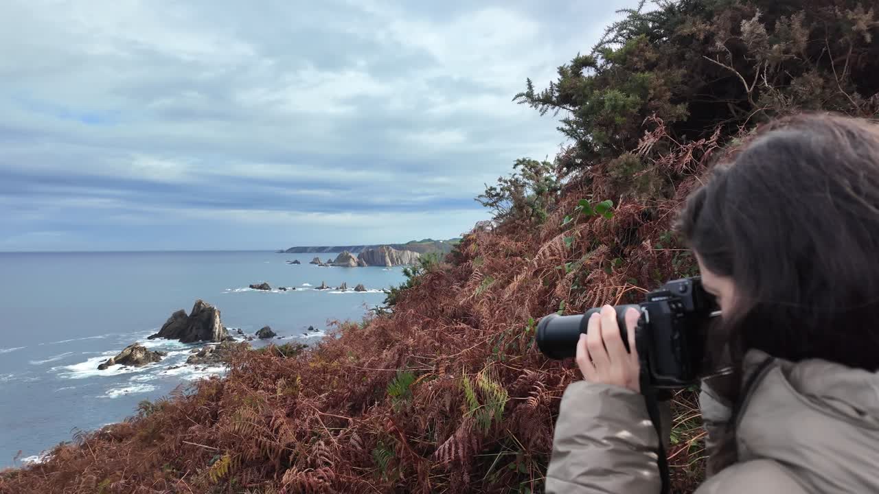 Slow-motion shot of a person taking photos over a rugged coastal landscape