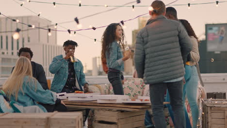 group of happy friends hanging out dancing together enjoying rooftop party at sunset drinking alcohol having fun on weekend celebration
