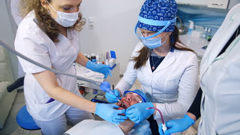 teaching the students of dentistry department. female doctor speaks to the students sitting near the patient. top view.