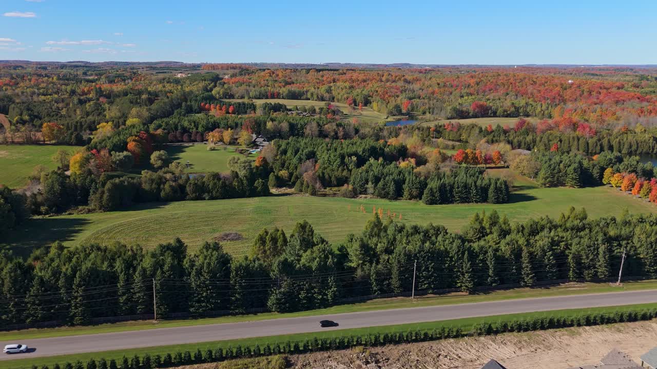 Aerial Flyover Of A New Housing Community Being Built With A Forest Of Fall Colours Behind In Caledon, Ontario, Canada