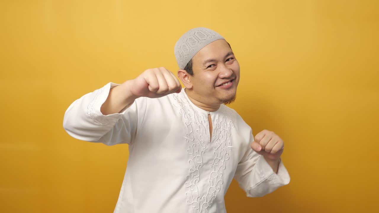 재미있는 젊은 아시아 무슬림 남자가 행복하게 춤을 추고, 기게 표현하고, 좋은 소식을 축하하고, 승리를 거두고, 성공적인 몸짓을 하고, 미소 짓고, 긍정적 인 흥분된 감정을 나타니다.