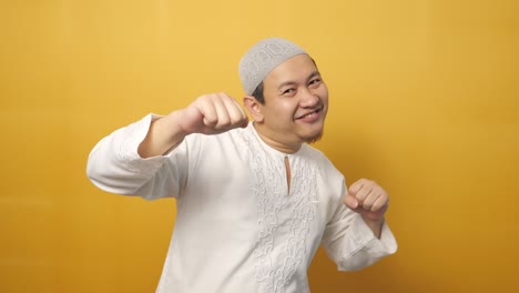 funny young asian muslim man dancing happily joyful expressing celebrating good news victory winning success gesture, smiling positive excited emotion