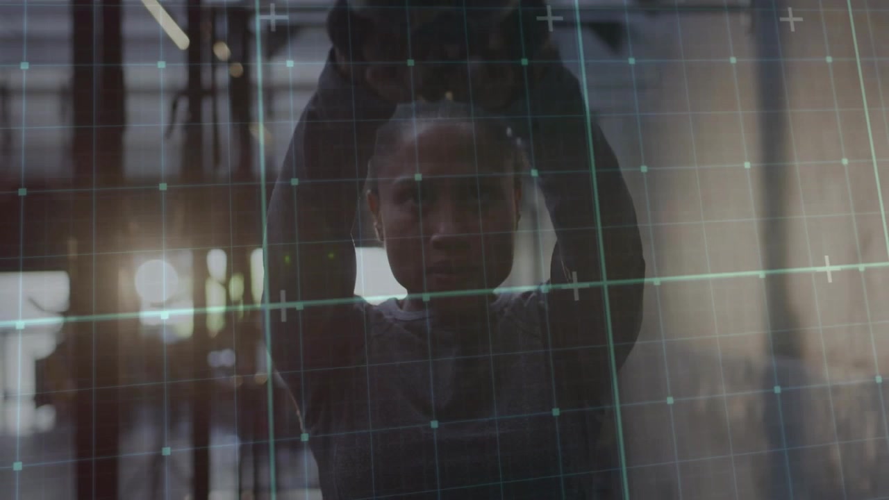 Woman rising into frame, lifting weight for training behind glass pane while teal HUD grid shifting