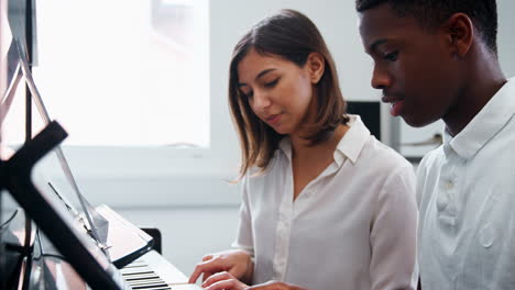 Männlicher-Schüler-Mit-Lehrer,-Der-Im-Musikunterricht-Klavier-Spielt