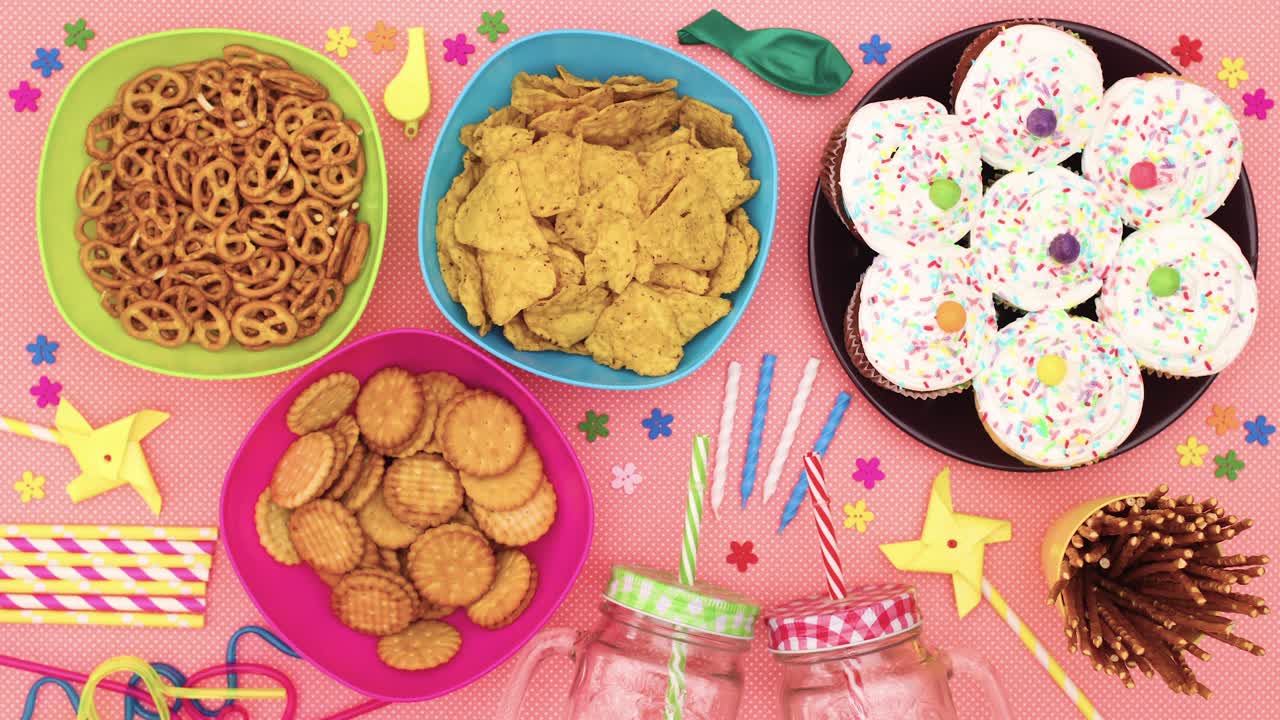 la comida y las decoraciones de la fiesta, los pasteles, las pajas, las velas, los globos aparecen en la mesa.