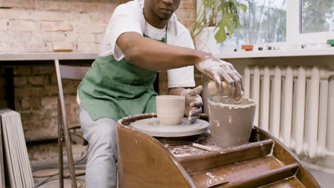 empleado americano modelando una pieza de cerámica en una rueda de alfarero en un taller 1