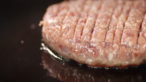 raw burger meat is fried with hot steam in a frying pan.