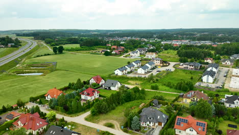 Aerial-view-of-a-suburban-residential-area,-featuring-modern-houses,-lush-greenery,-and-surrounding-open-fields,-depicting-a-serene-and-spacious-living-environment