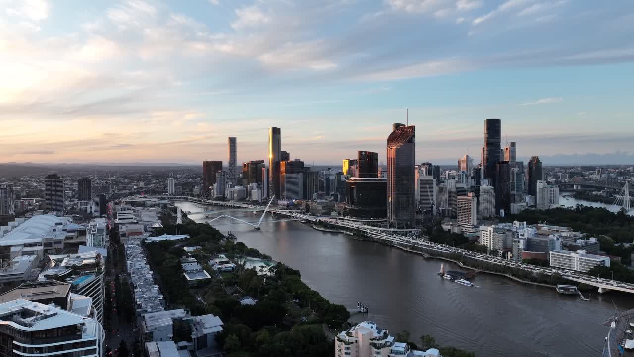 Langsom dronetur langs Brisbane-floden ved den gyldne time, der glider forbi Queens Wharf og The Star Brisbane med CBD's skyline og South Bank i syne, Brisbane, QLD, Australien