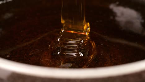 fresh honey flowing  into a bowl on the black background. healthy organic thick honey closeup, sweet honey dessert 4k