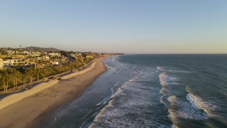 Luftaufnahme-Des-Schönen-Ozeans-Mit-Leerem-Sandstrand,-Palmen-Und-Promenade-Während-Des-Sonnenuntergangs