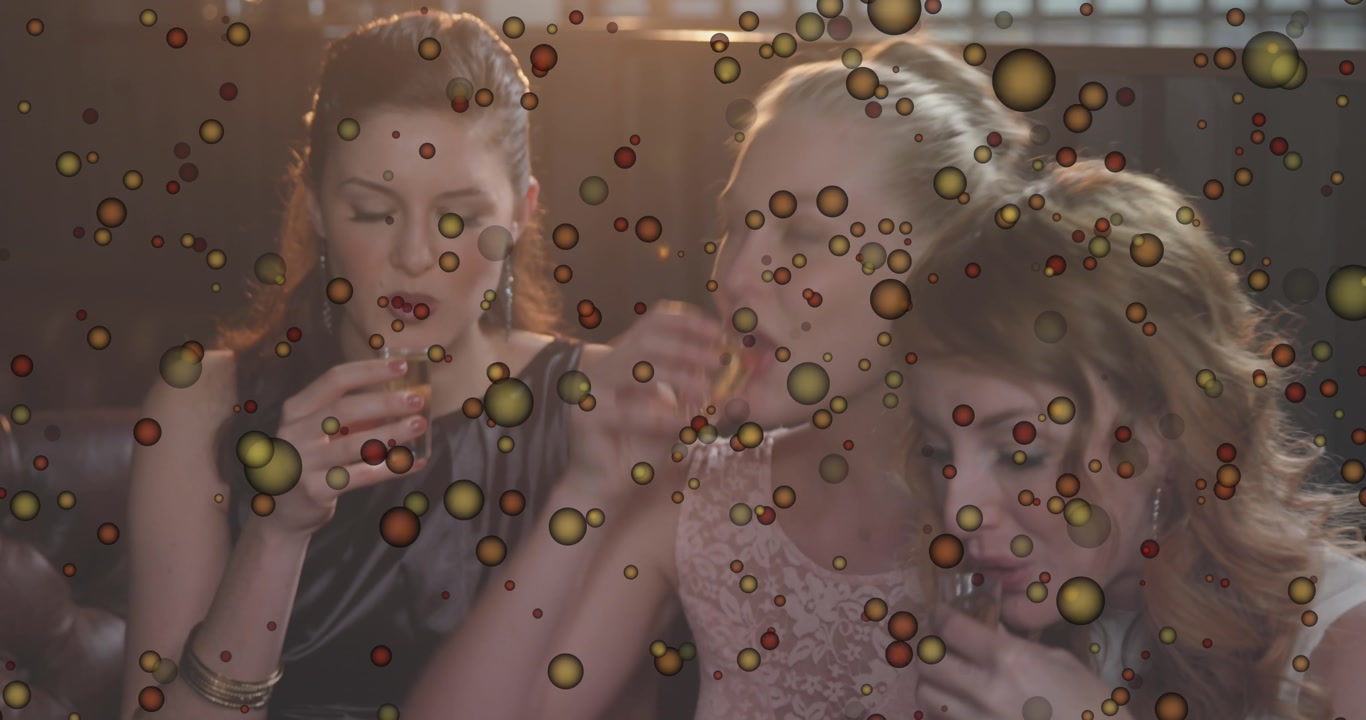 Animation of yellow spots bouncing over three female friends toasting and drinking shots at a bar