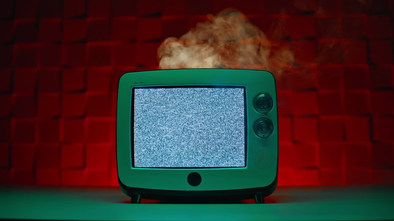 Stary telewizor analogowy dymi, migocze białym szumem na kolorowym tle z bliska
