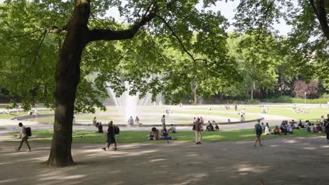 벨기에 브셀의 주빌리 공원 (jubilee park) 에 있는 물 분수 (fountain) 를 가진 광장 (square de la bouteille) 에서 사람들이 어울리고 있다.