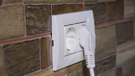 side view of a man hand plugging and unplugging from the european model wall power socket