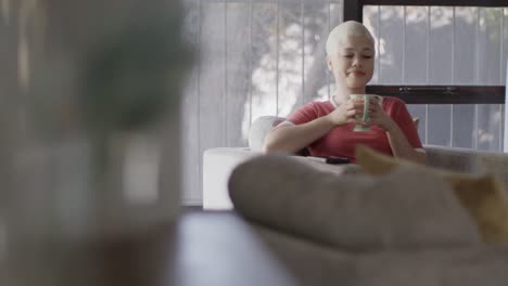 Happy-biracial-woman-drinking-coffee-at-home-in-slow-motion