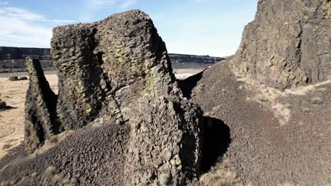 flying through ancient basalt columns to reveal the bleak desert canyon below, aerial