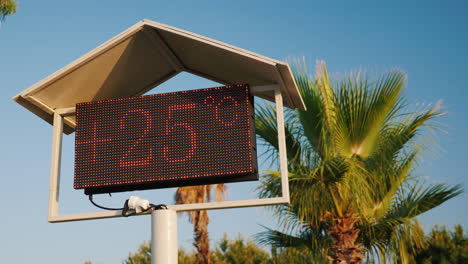 the thermometer's scoreboard on the beach shows the temperature is 25 degrees celsius