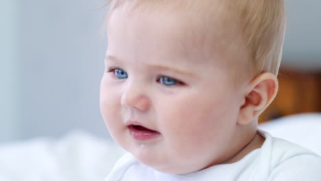 close up of happy baby boy sitting on parents bed