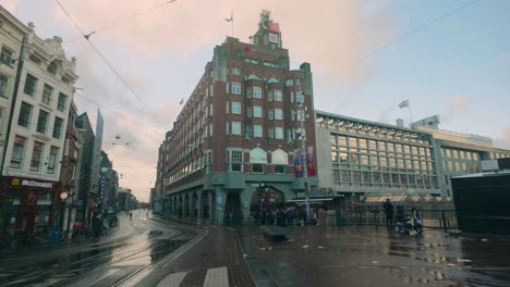 morning scene in amsterdam with iconic brick architecture, wet streets, and soft pastel skies. a classic blend of historic and modern buildings highlights urban charm and rainy tranquility.