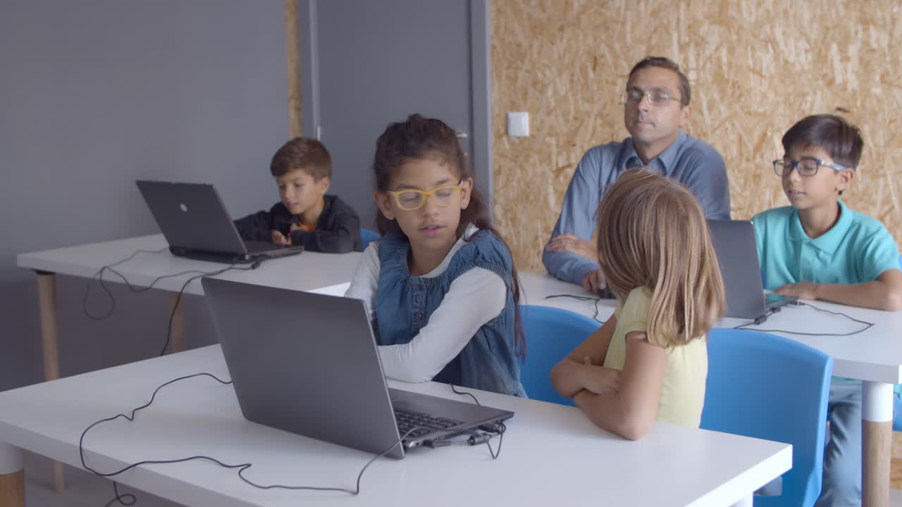 el maestro sentado en el escritorio cerca del niño de la escuela
