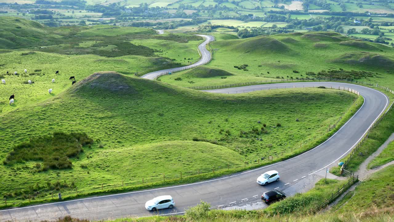 Fixed shot of two cars driving up the Peak Districts famous Snake Pass