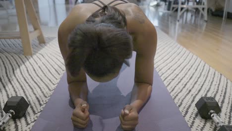 a rising shot of a black female holding a plank in her living room while looking at her lap top