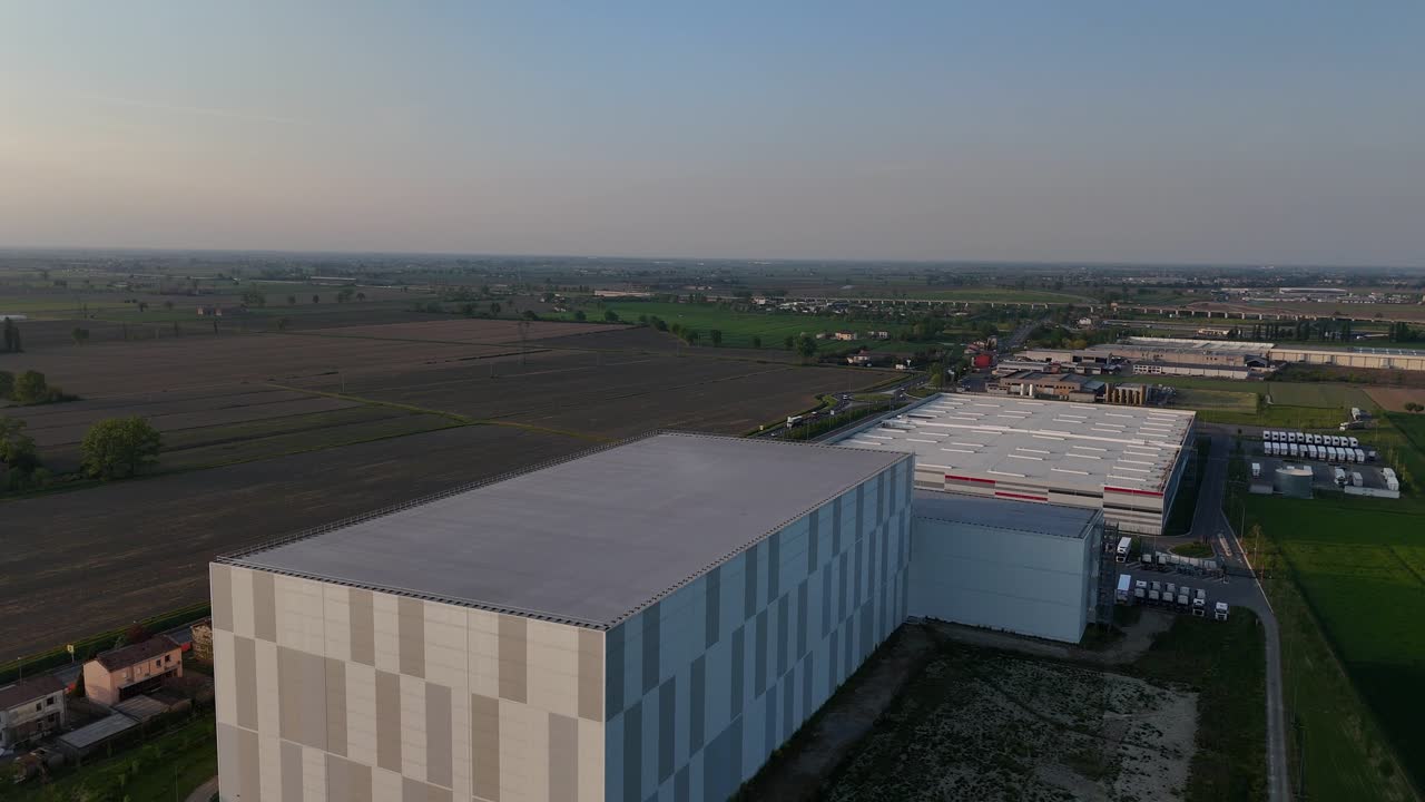 Data center and logistics complex in Pianura Padana near Piacenza Emilia Romagna Italy surrounded by extensive agricultural fields and infrastructure within flat Po Valley plain, drone aerial shot