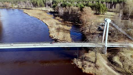 Riga,-Lettland,-Europa-–-Menschen-überqueren-Die-Vansu-Tilt-–-Eine-Bemerkenswerte-Schrägseilbrücke-über-Den-Fluss-Daugava-–-Schwenk-Nach-Links