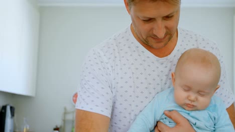 padre alimentando leche a su bebé en la cocina 4k