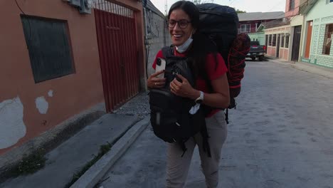 Hispanic-woman-with-two-heavy-back-packs-dances,-twirls-on-HDN-street