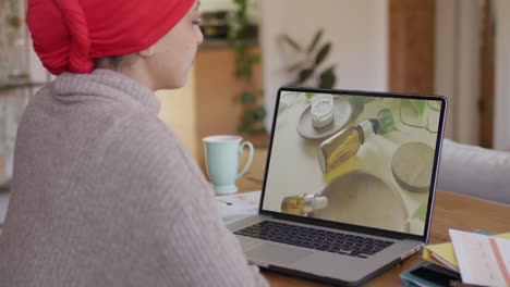 biracial woman at table using laptop, online shopping for aromatherapy products, slow motion