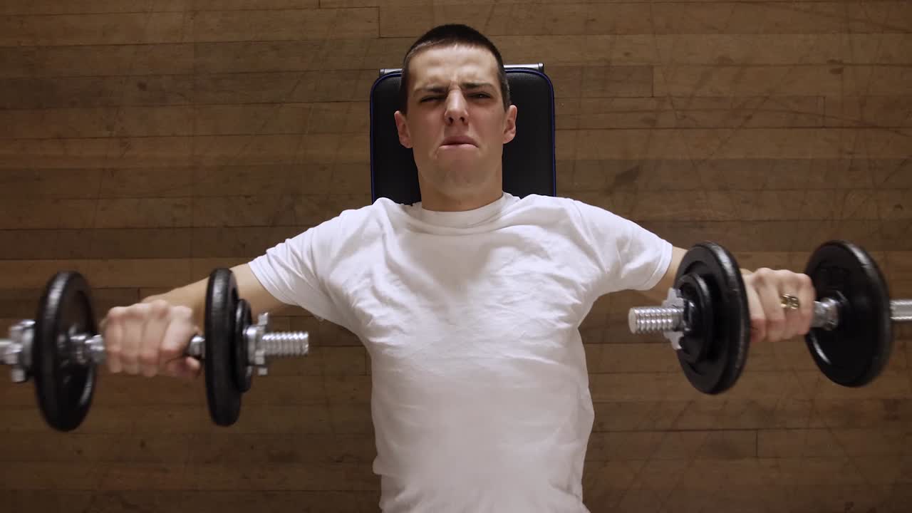 더 크고 강한 가슴을 만들기 위해 멍청한 벨 벤치 프레스 루틴을 수행하는 강한 남자 - 클로즈업 탑 샷