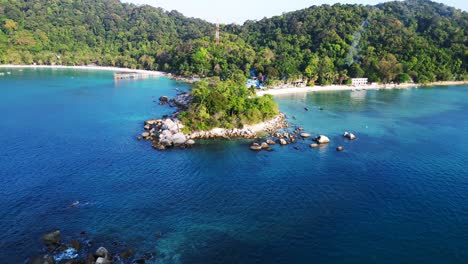 Gorgeous-aerial-view-flight-of-a-Hut-on-a-tropical-Sole-peninsula-with-turquoise-water-and-lush-green-vegetation