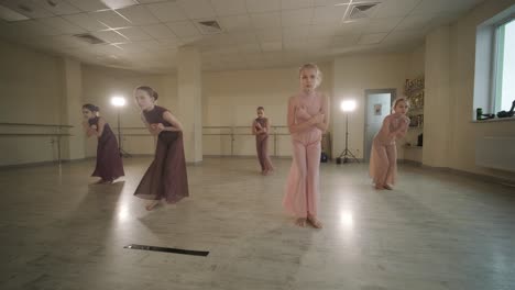 a group of young ballet students in black dancewear practicing positions in a spacious ballet studio with wooden flooring and wall-mounted barres. focused expressions and synchronized movements.