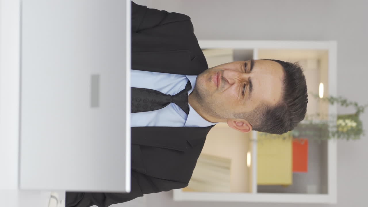 Vertical video of Home office worker man looking at camera with disgust and hatred.