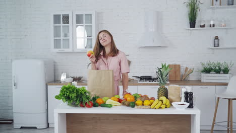 Woman with orange and apple in her hands indoors. Beautiful housewife chooses an apple to eat. Healthy food concept. Vertical video