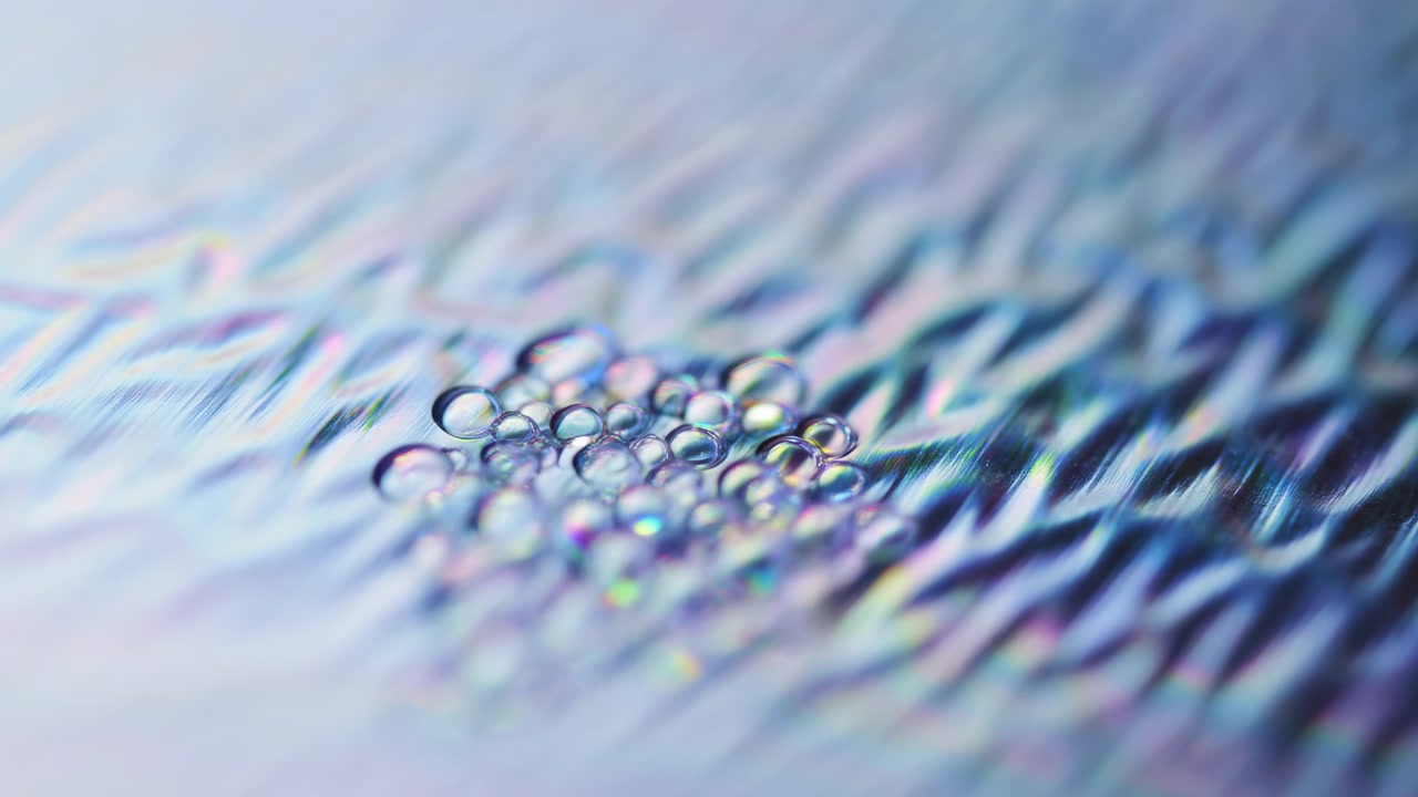 Macro time-lapse che mostra la progressione da una superficie riflettente increspata iniziale alla formazione di goccioline d'acqua raggruppate, espansione delle increspature verso l'esterno, gocciolina.