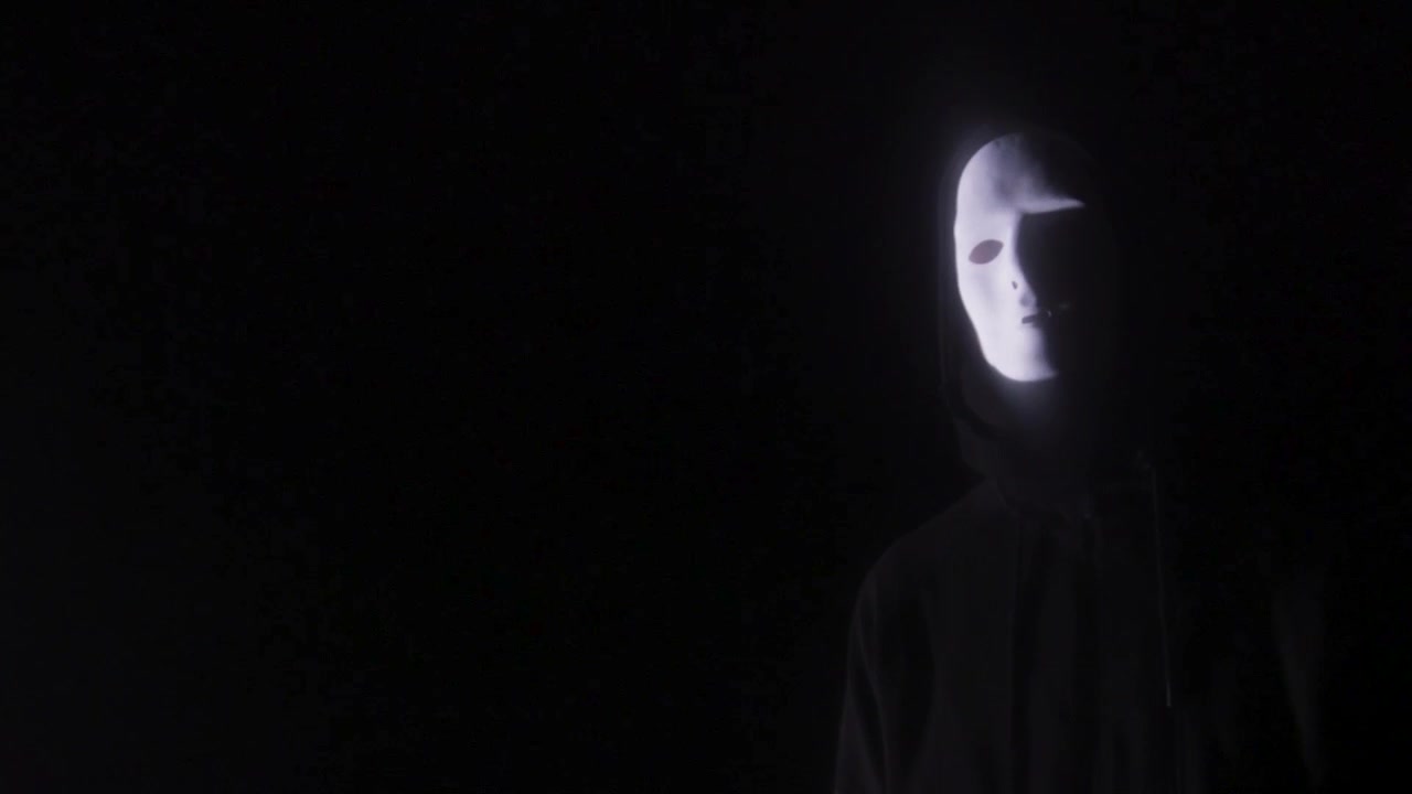 Naamioitu mies seisoo pimeydessä kirkasta valoa vasten luoden aavemaisen Halloween-kauhutunnelman jännitys-, trilleri- ja yliluonnolliseen sisältöön.