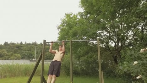 athletic young man reps pullups on home outdoor gym slow-motion