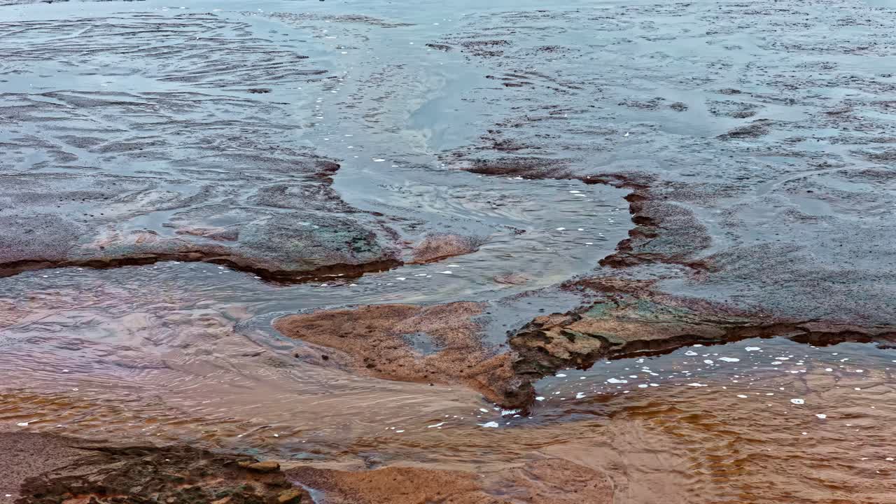 Mud flats and shallow river channels exposed in dry season, drone follows flow of water